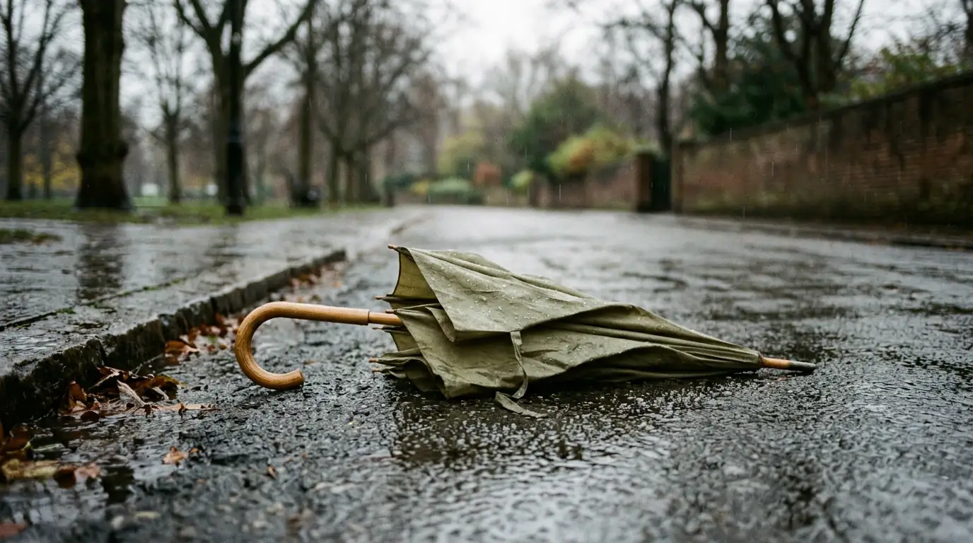 Paraguas a medio cerrar bajo una lluvia leve, evocando protección que se pierde